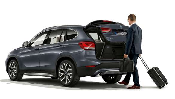 BMW X1, sjálfvirkur afturhleri. BMW X1, hliðarsýn með manni sem stendur við afturhlera í opinni stöðu.