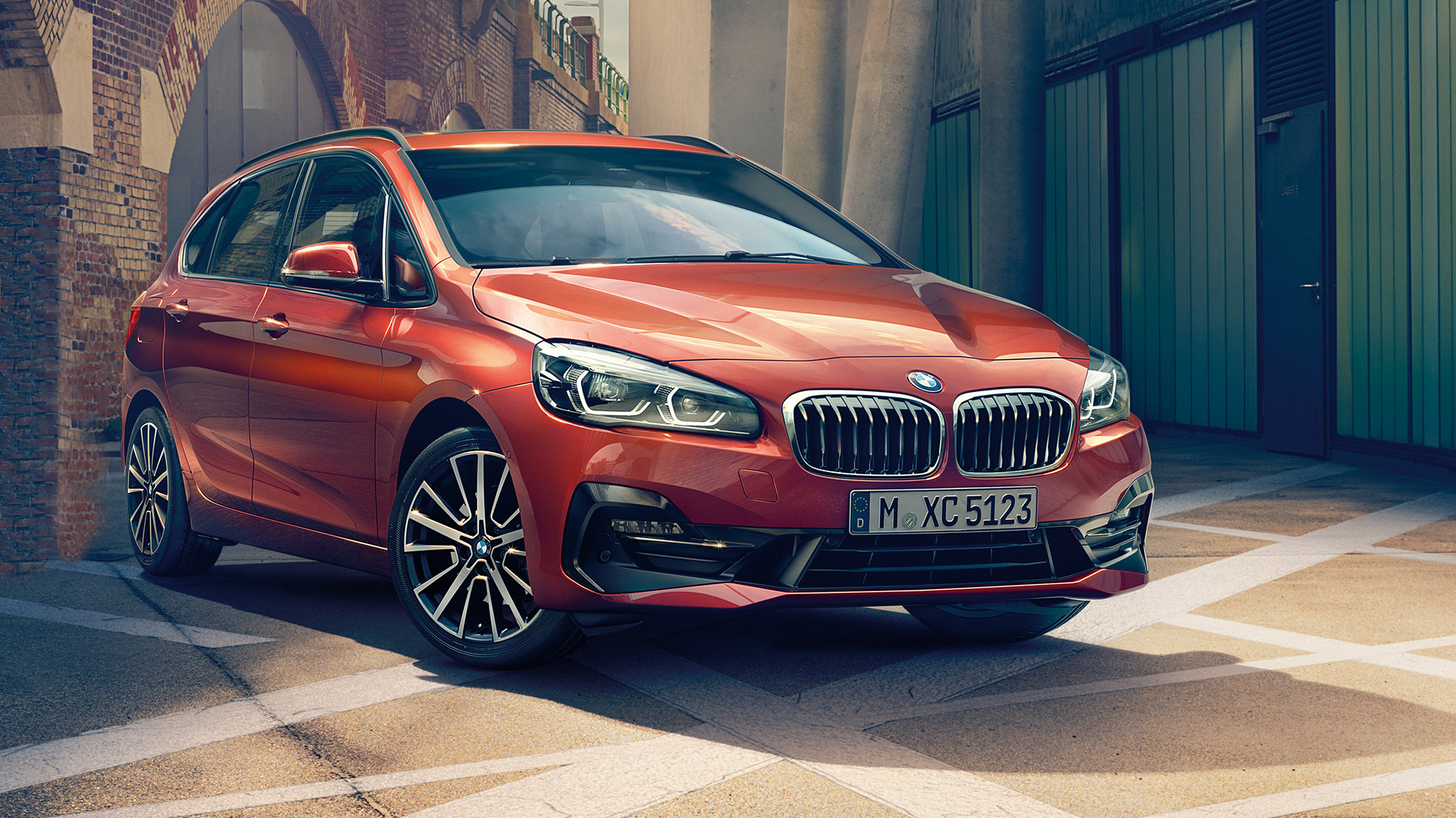 Ytra byrði BMW 2 Series Active Tourer Sanseraður sólsetursappelsínugulur BMW 2 Series Active Tourer F45 Facelift 2018, skásett sjónarhorn á framhluta í húsasundi