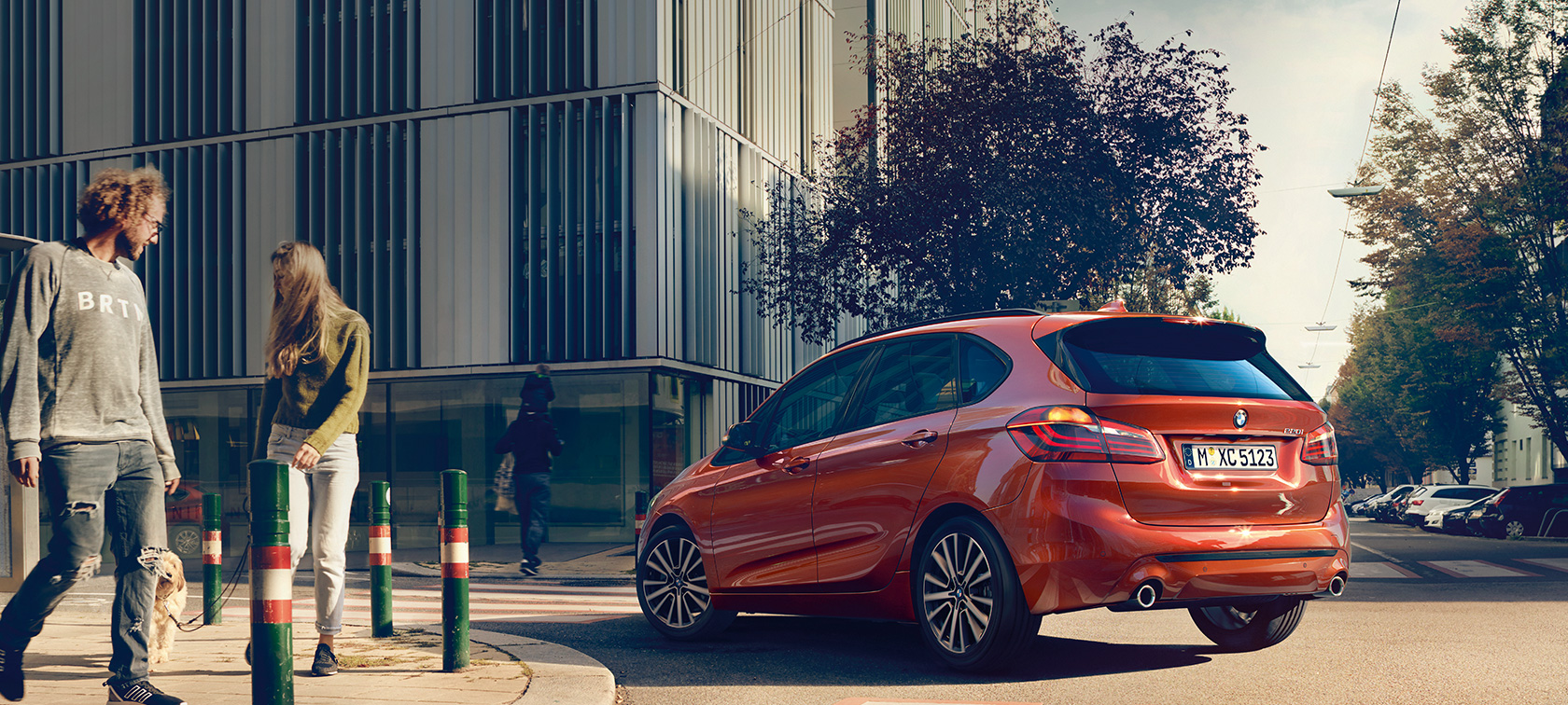 Skásett sjónarhorn á afturhluta BMW 2 Series Active Tourer 220i Sanseraður sólsetursappelsínugulur BMW 2 Series Active Tourer 220i F45 Facelift 2018, skásett sjónarhorn á afturhluta við akstur á vegi