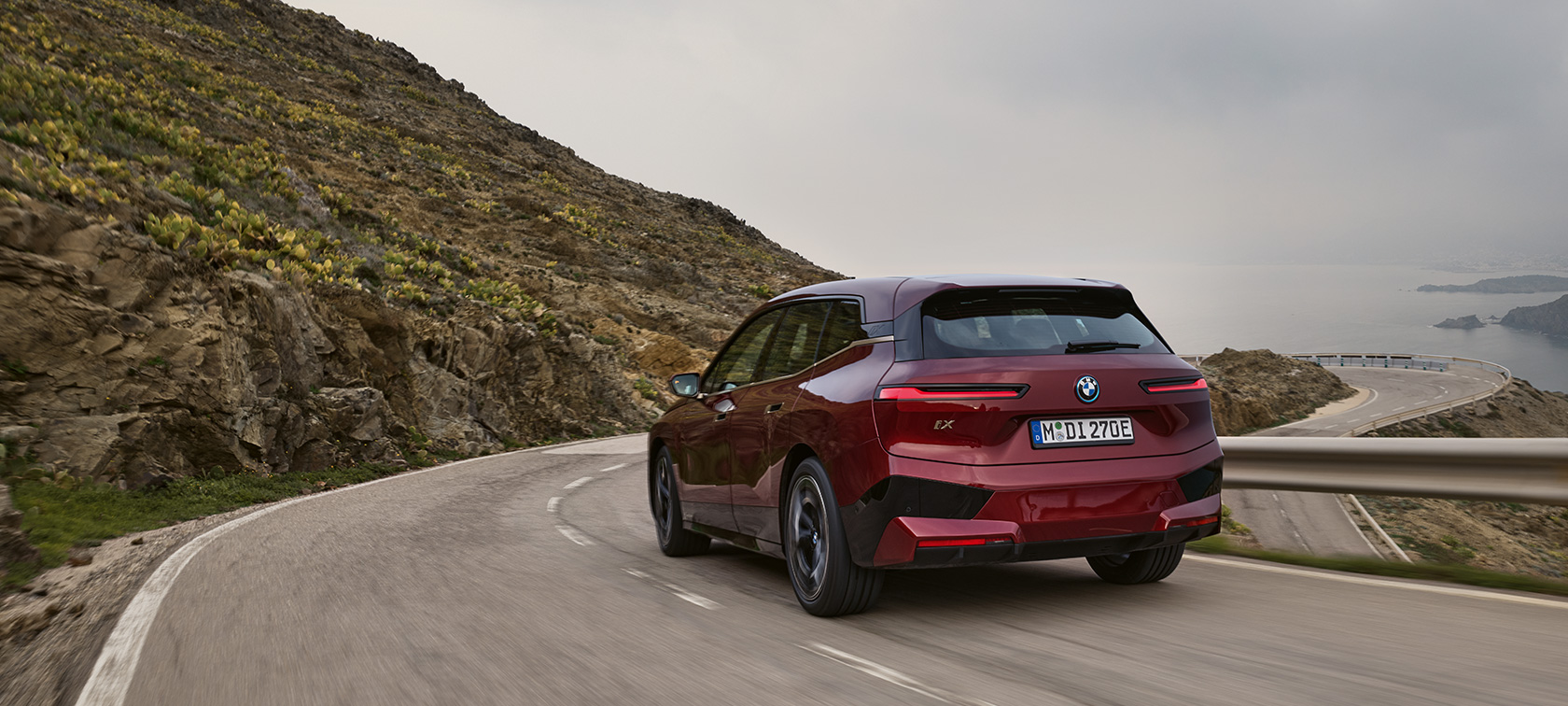 BMW iX i20 2021 rafmagnsjeppi BMW iX xDrive50 akstur á strandvegi BMW iX i20 2021 rafknúinn jeppi BMW iX xDrive50 Aventurin Rauður aftursýn akstur á strandvegi
