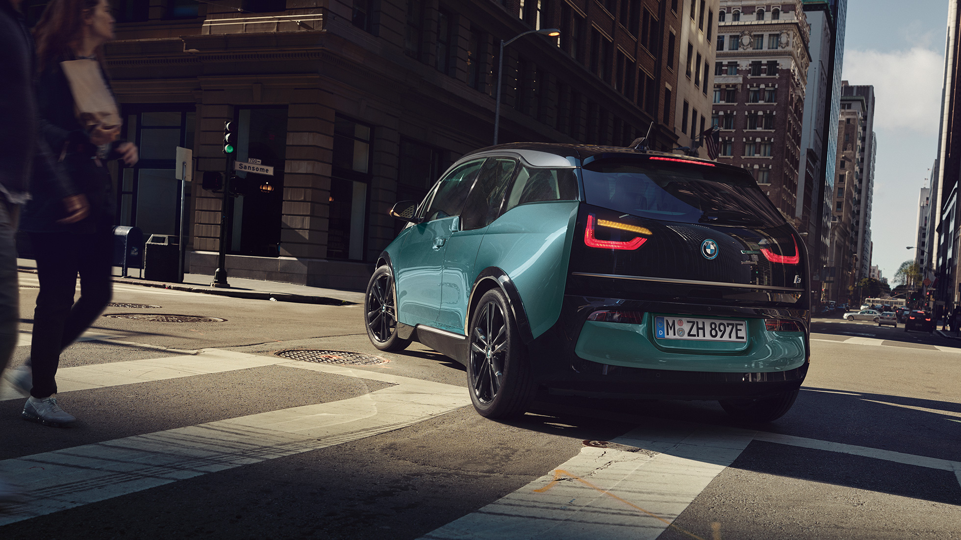 BMW i3 2018 í akstri, skásett sjónarhorn á afturhluta BMW i3 I01 2018, Jucaro-drapplitaður með frostgráum sanseruðum áherslulit, skásett sjónarhorn á afturhluta í innanbæjarakstri