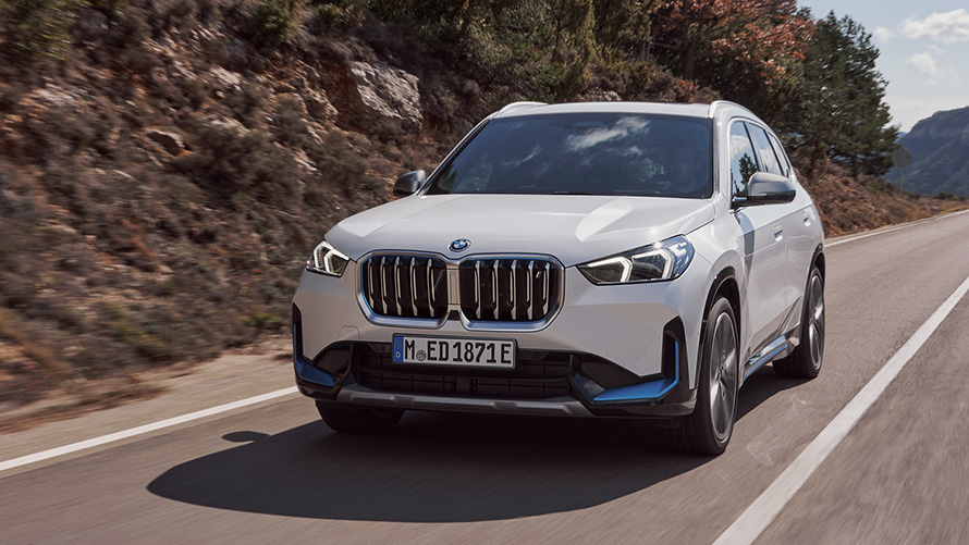 Fyrsta kynslóð BMW iX1 U11 ekur á götu, skásett sjónarhorn á framhluta BMW X-línan – fyrsta kynslóð BMW iX1 U11 ekur á götu, skásett sjónarhorn á framhluta