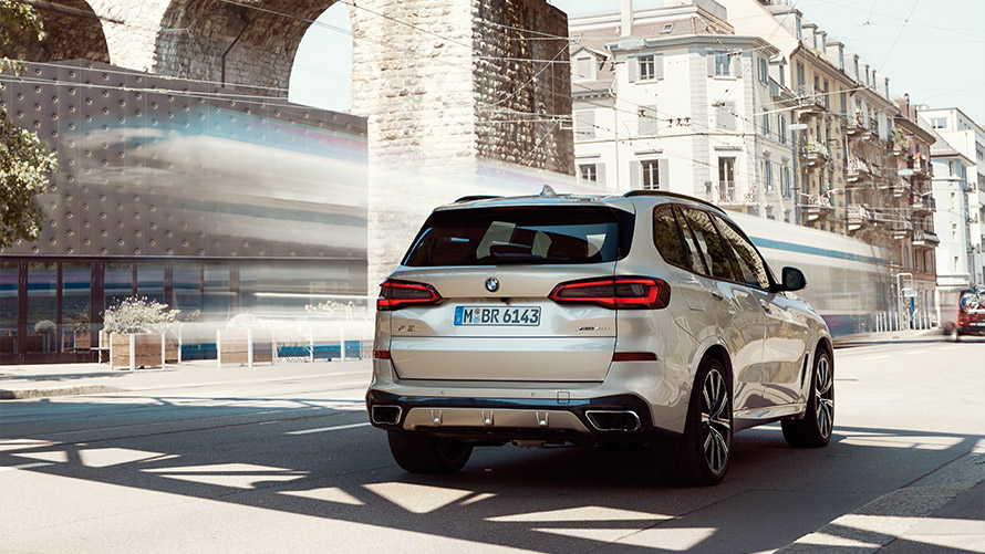 Fjórða kynslóð BMW X5 G05 í kyrrstöðu fyrir framan byggingu, skásett sjónarhorn á afturhluta BMW X-línan – fjórða kynslóð BMW X5 G05 í kyrrstöðu fyrir framan byggingu, skásett sjónarhorn á afturhluta