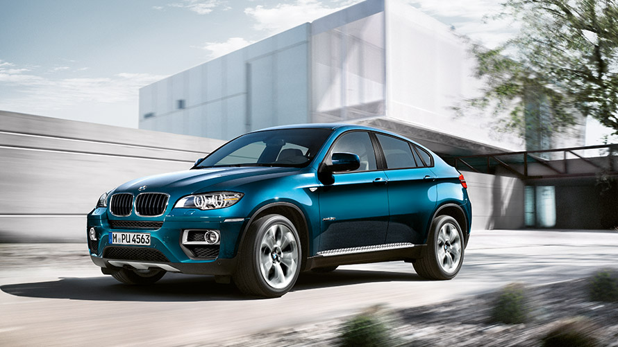 Fyrsta kynslóð BMW X6 E71 í kyrrstöðu fyrir framan byggingu, skásett sjónarhorn á hlið BMW X-línan – fyrsta kynslóð BMW X6 E71 í kyrrstöðu fyrir framan byggingu, skásett sjónarhorn á hlið