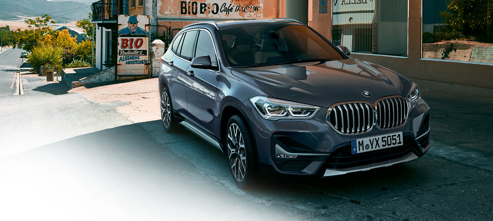 BMW X1, skásett sjónarhorn á framhluta. BMW X1, skásett sjónarhorn á framhluta með þéttbýli í bakgrunni.