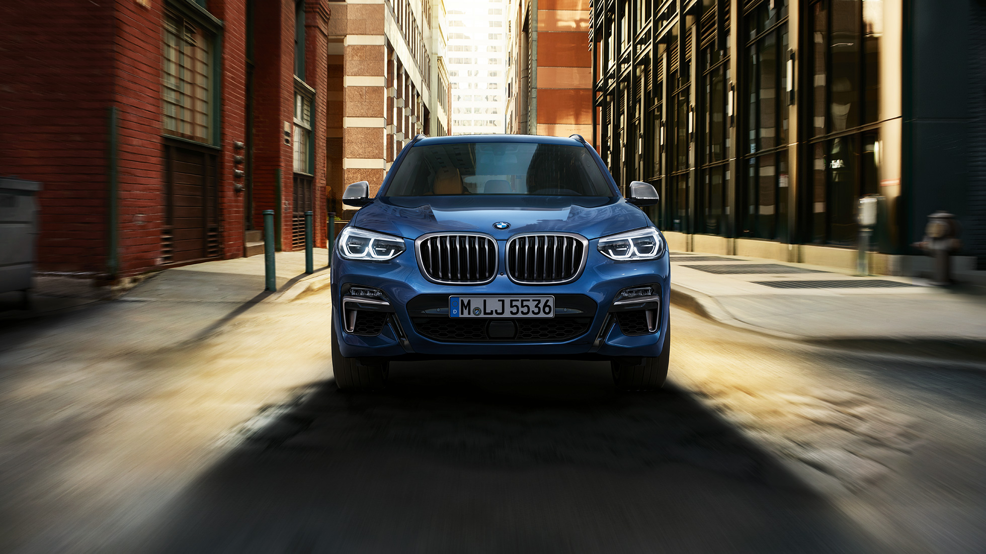 BMW X3 M40i, sjónarhorn á framhluta fyrir framan borgarlandslag BMW X3 M40i, sjónarhorn á framhluta fyrir framan borgarlandslag