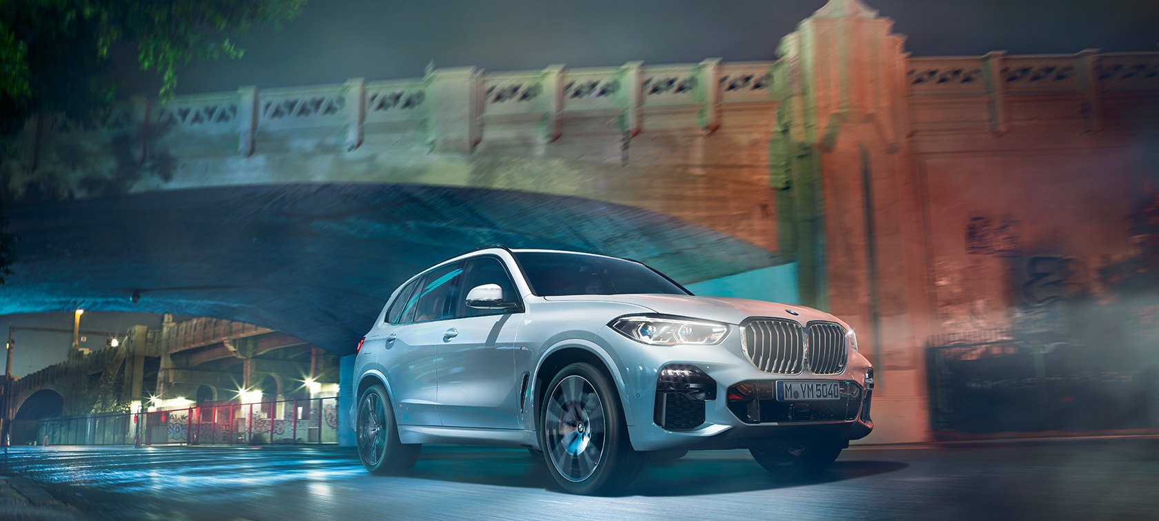 Steinhvítsanseraður BMW X5 G05 2018, skásett sjónarhorn á framhluta í akstri í myrkri