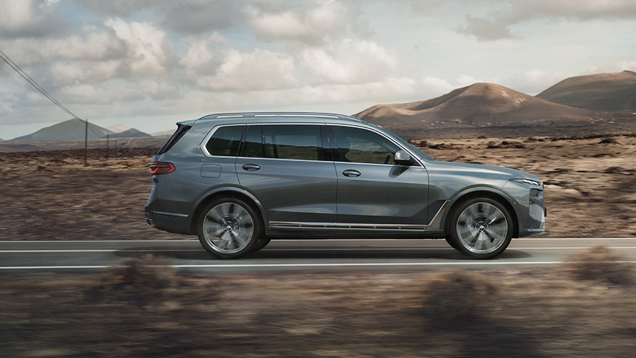 Sindrandi kopargrásanseraður BMW X7 G07 LCI, frá hlið Sindrandi kopargrásanseraður BMW X7 G07 LCI á ferð, frá hlið