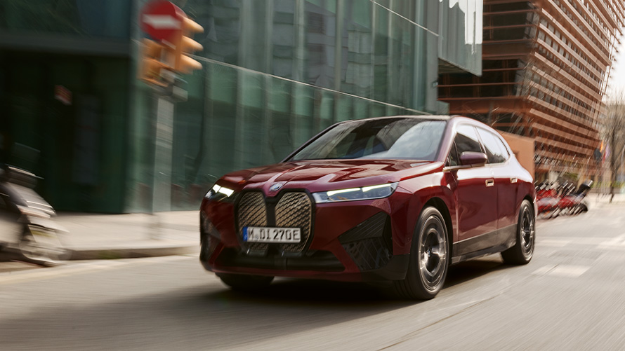 BMW iX3 G08 2021, skásett sjónarhorn á framhluta BMW iX3 G08 2021 ekur fyrir framan hæðótt landslag í þoku, skásett sjónarhorn á framhluta