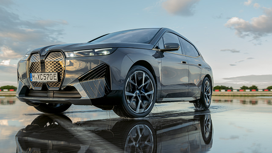 BMW-felgur, skásett sjónarhorn á framhluta BMW iX (i20) á blautri götu BMW-felgur, skásett sjónarhorn á framhluta BMW iX (i20) á blautri götu