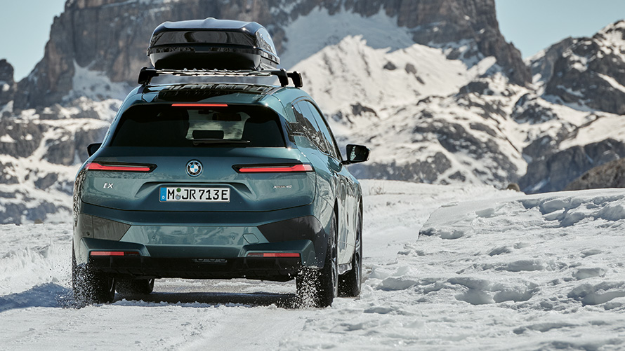 BMW-felgur með vetrarhjólarbörðum á BMW iX (I20) á snæviþöktum vegi með fjöll í bakgrunni BMW-felgur með vetrarhjólarbörðum á BMW iX (I20) á snæviþöktum vegi með fjöll í bakgrunni
