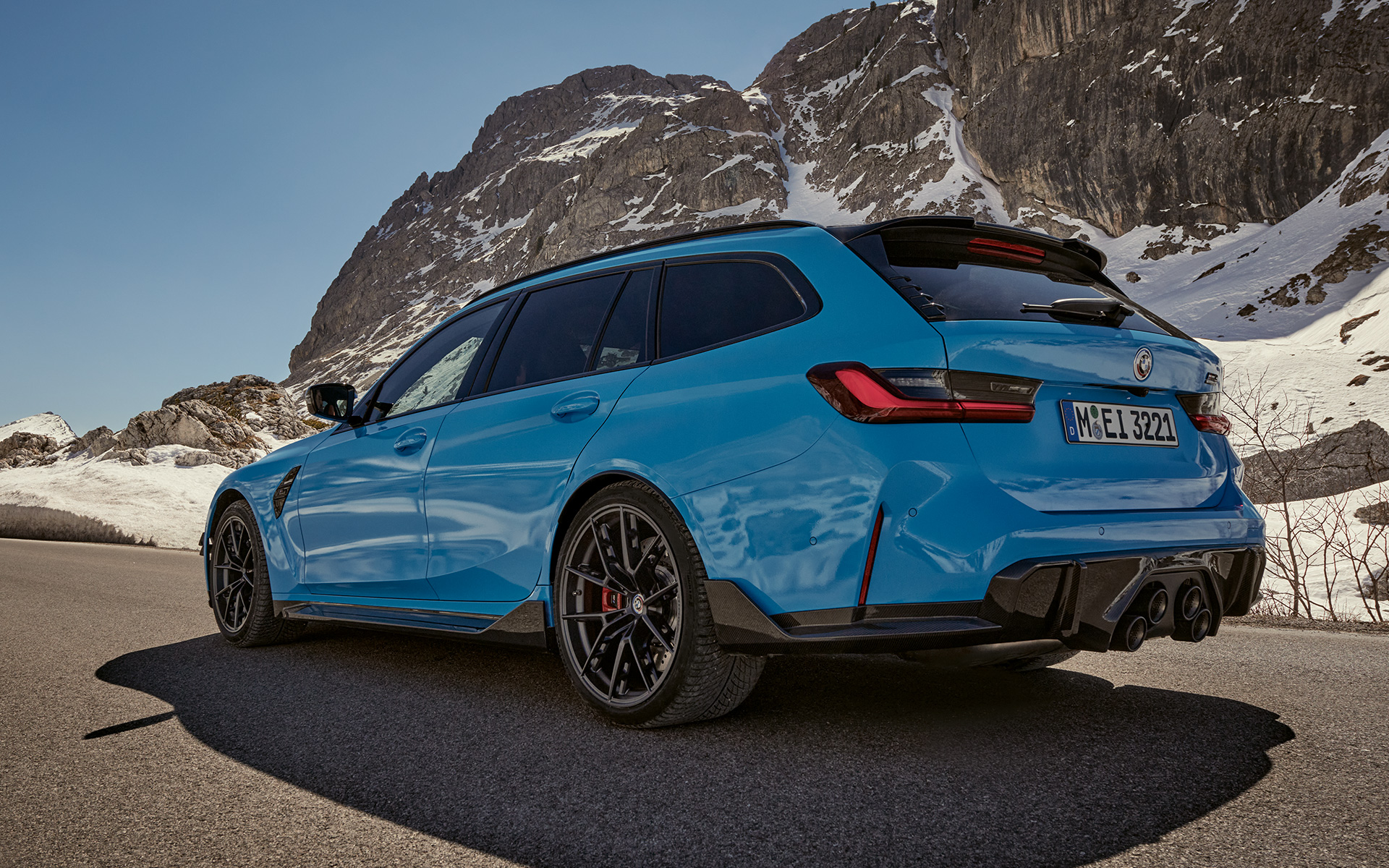 BMW M3 Touring G81 BMW M Performance-búnaður í akstri, skásett sjónarhorn frá hlið með fjallasýn að baki