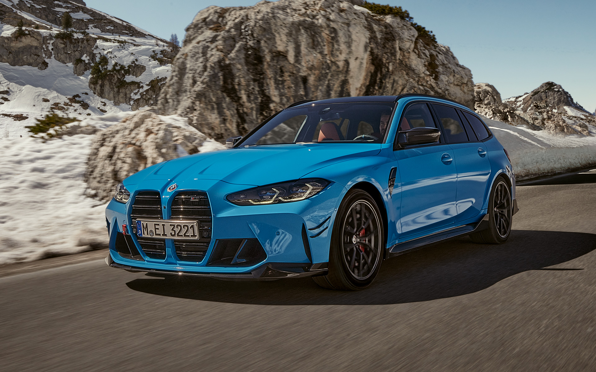 BMW M3 Touring G81 BMW M Performance-búnaður í akstri, skásett sjónarhorn á framhluta með fjallasýn að baki