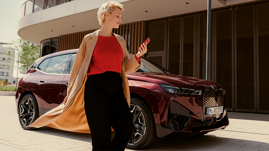 My BMW-forritið Kona með snjallsíma fyrir framan BMW-bíl Kona með snjallsíma fyrir framan BMW-bíl