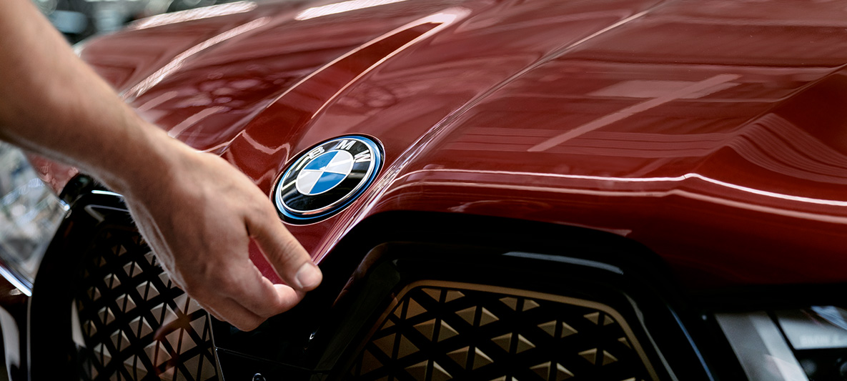 Skoðun og viðhald BMW Hönd starfsmanns skoðunar- og viðhaldsdeildar BMW á húddi BMW-bíls