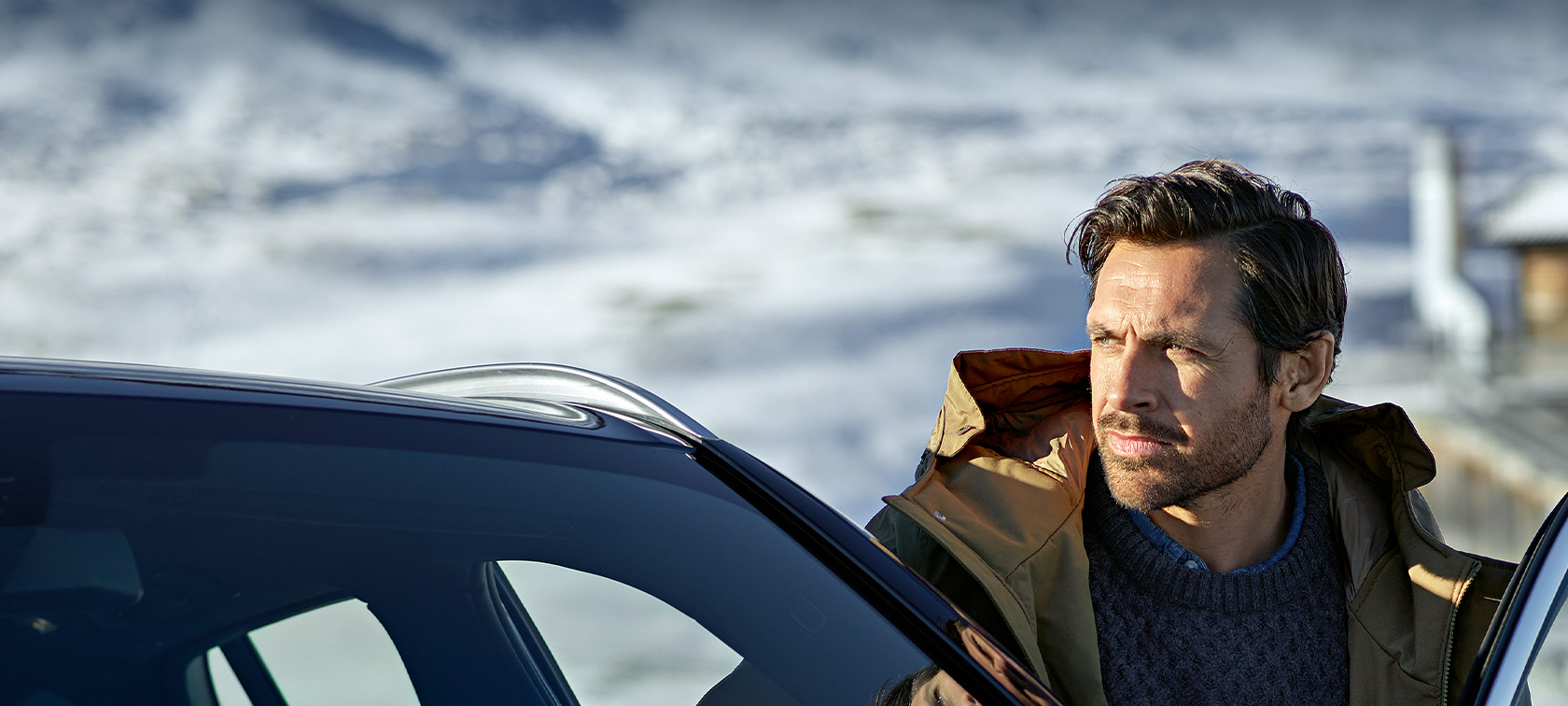 Original BMW Accessories and BMW Services for autumn and winter Man with winter parka standing in the door of his BMW