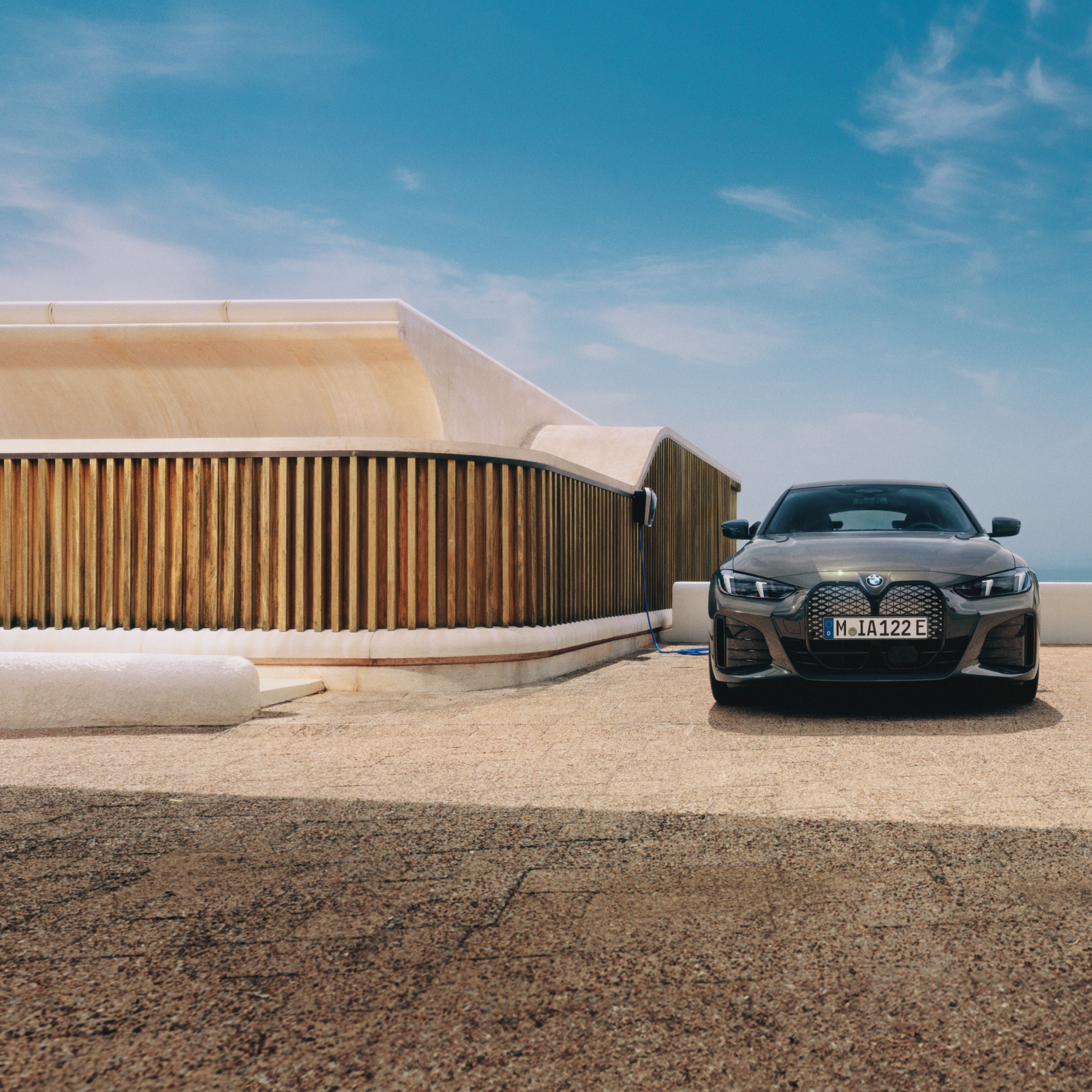 Maður með snjallsíma stendur við hlið BMW i4 sem er tengdur við Wallbox