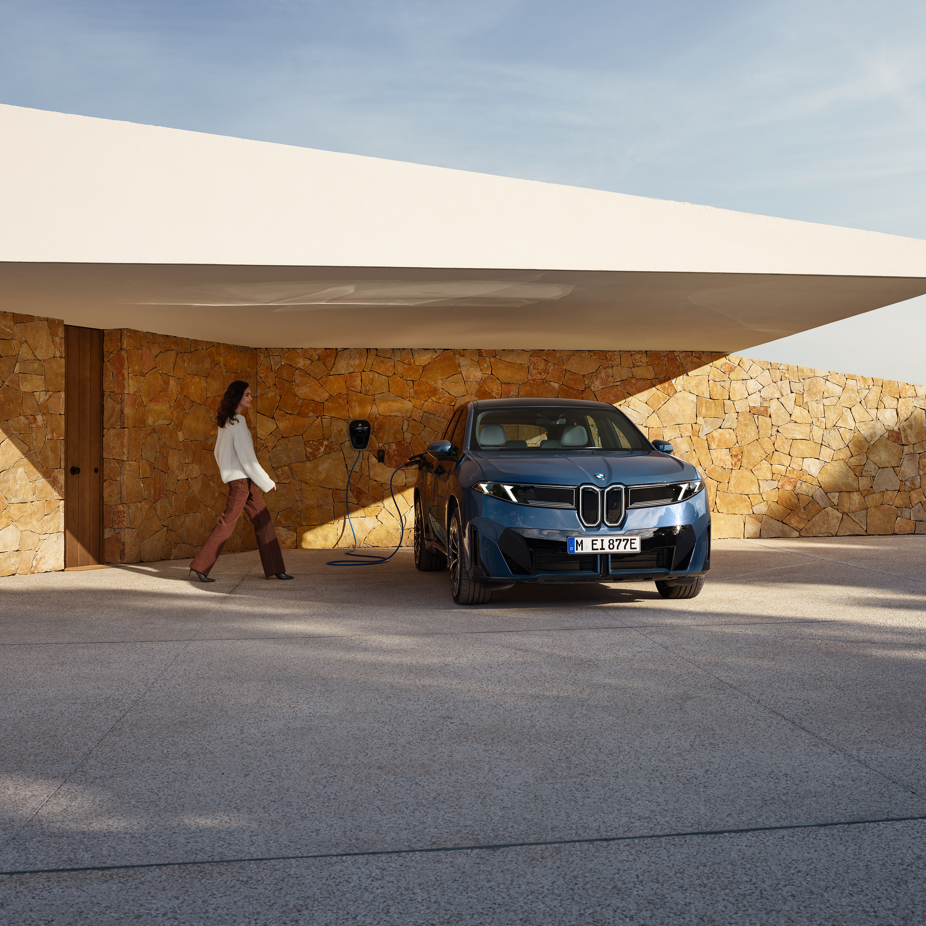 Kona gengur að BMW iX3 sem er tengdur við Wallbox
