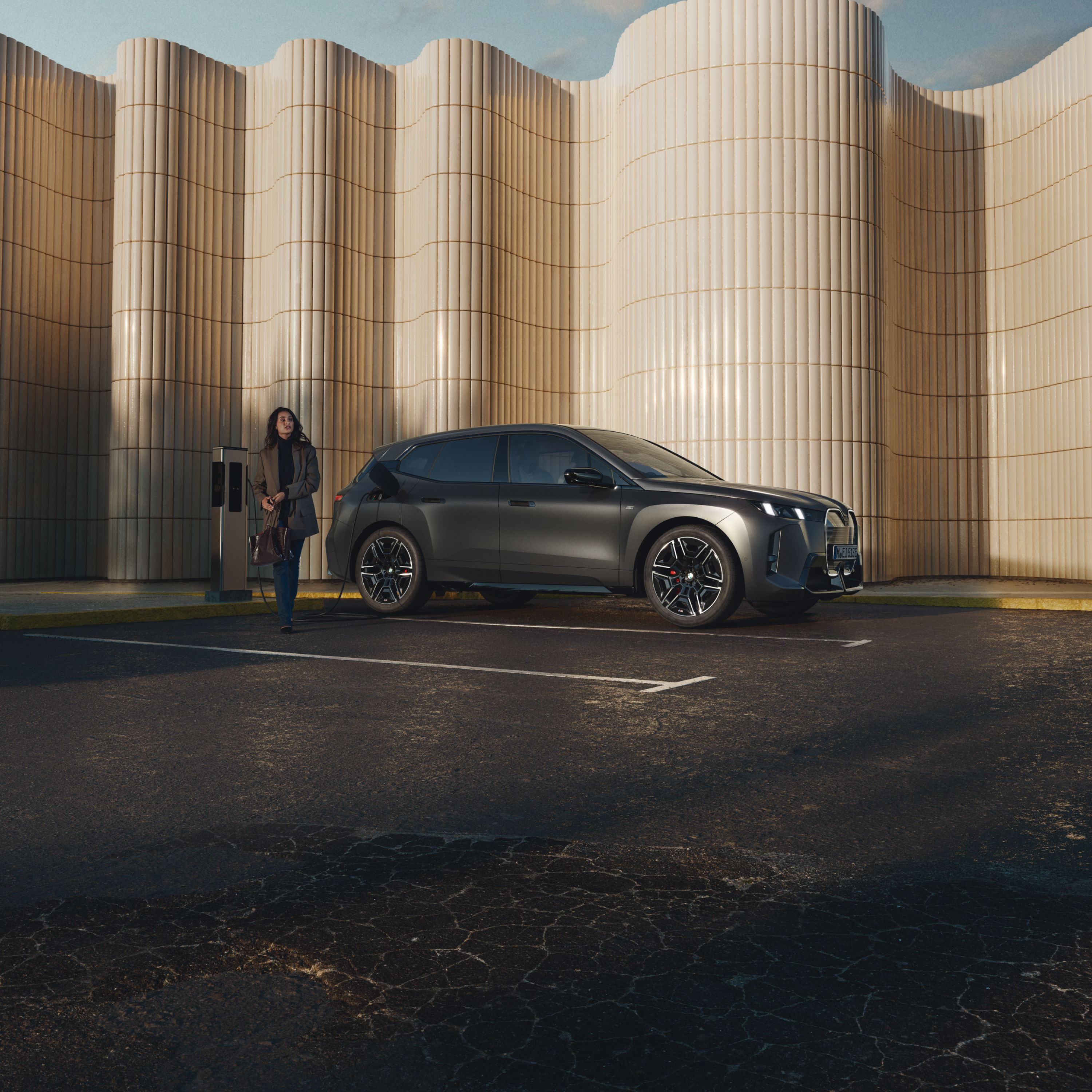 Einstaklingur hallar sér upp að BMW við almenna hleðslustöð við vegkantinn
