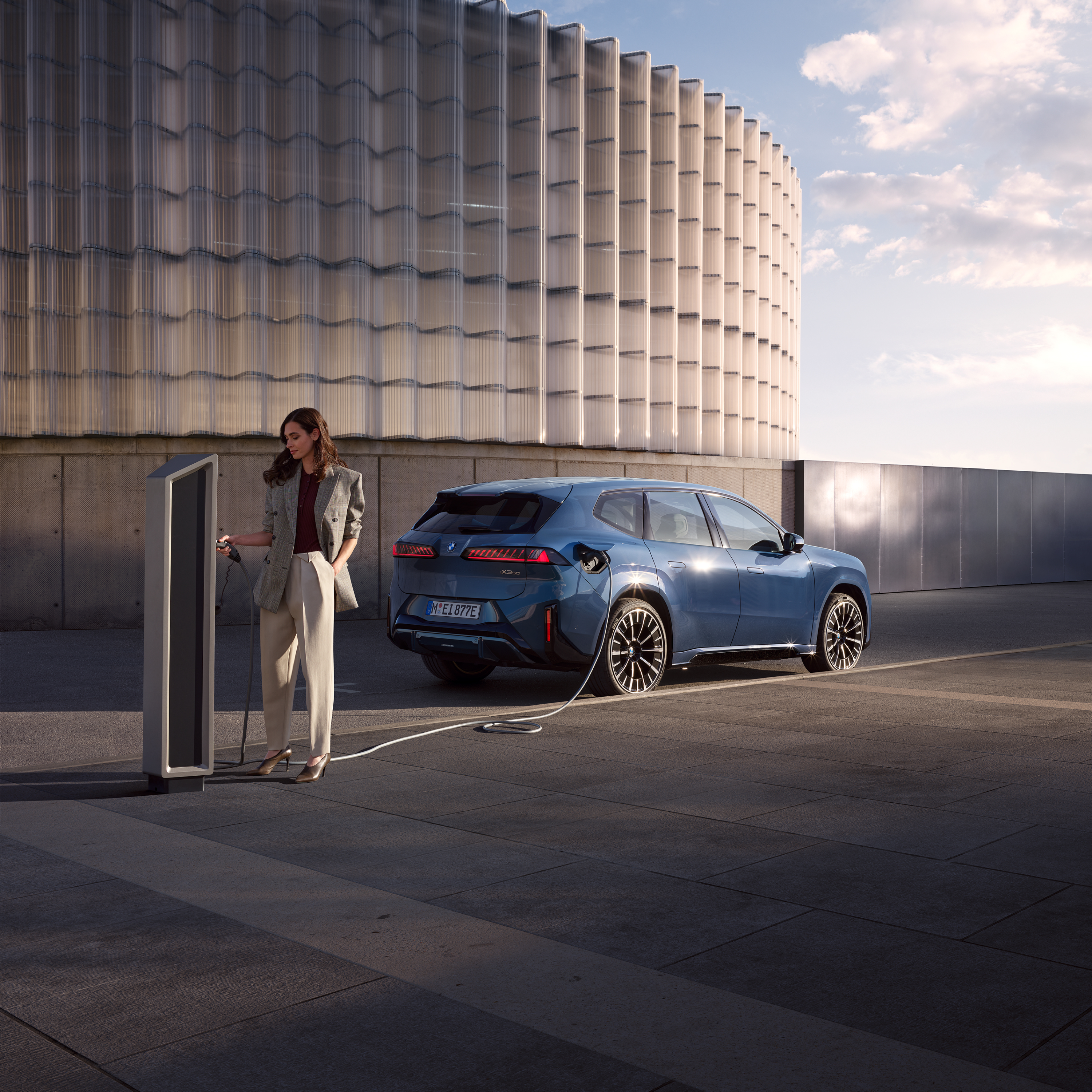 Kona stendur við hlið BMW iX3 sem er tengdur við almenna hleðslustöð